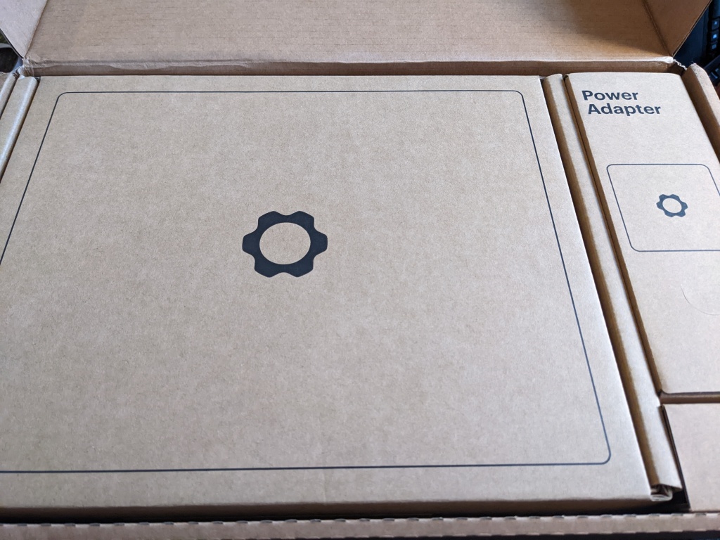 A nice cardboard box with the gear-shaped Framework logo on it.