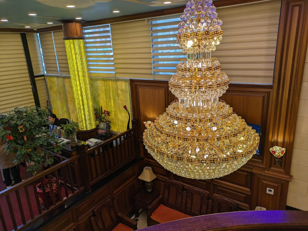 The shiny chandelier on the ceiling of the Allen Hotel's lobby, seen from the upstairs elevator level.